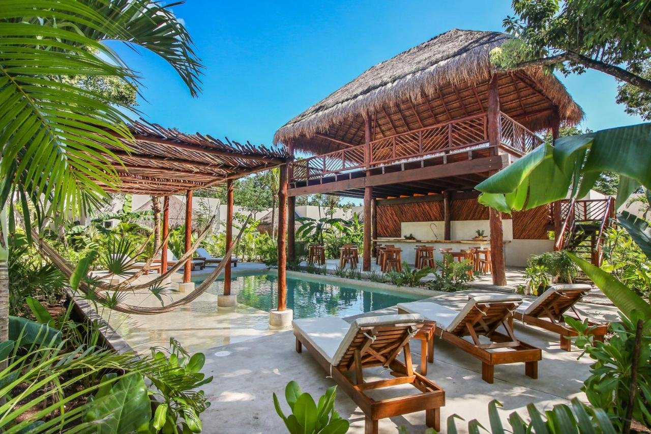 Tulum yoga retreat pool area with palapa-covered deck, hammocks, and tropical garden perfect for relaxation after yoga sessions