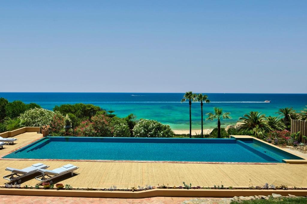 Vila Joya Algarve luxury pool with turquoise Atlantic Ocean views, palm trees and pristine Praia de Galé beach Portugal